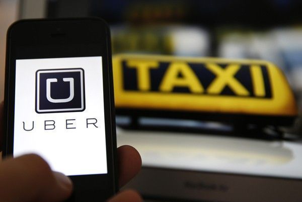 File illustration picture showing the logo of car-sharing service app Uber on a smartphone next to the picture of an official German taxi sign